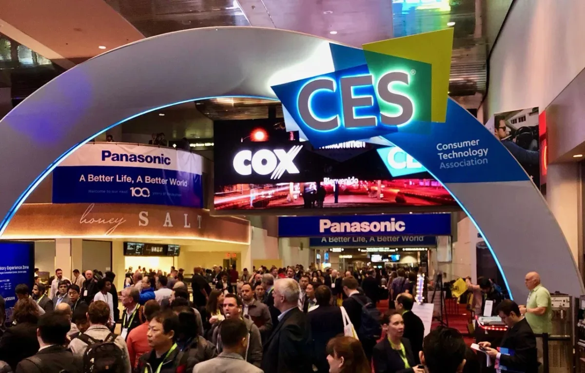 Entrada principal da CES, em Las Vegas, com o arco iluminado da feira e uma multidão de participantes credenciados